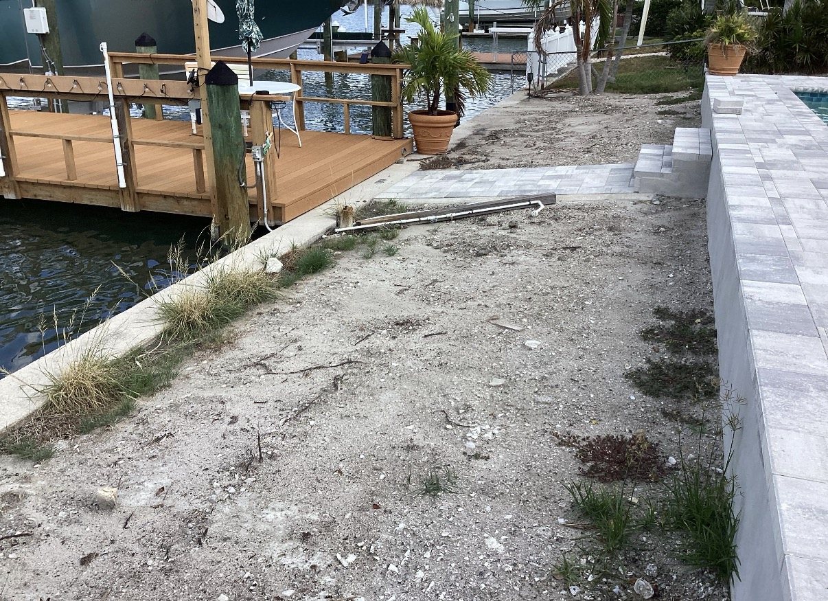 Bare waterfront ground beside Ed Brusic's Clearwater patio before artificial turf installation