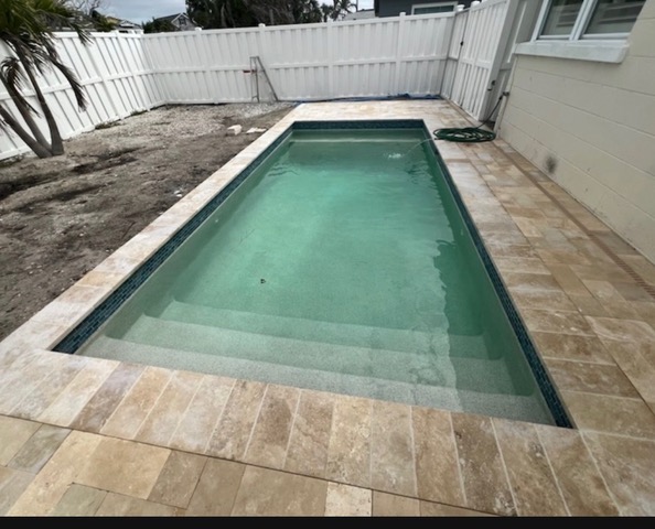 Poolside backyard before artificial turf, showing bare ground beside the pool