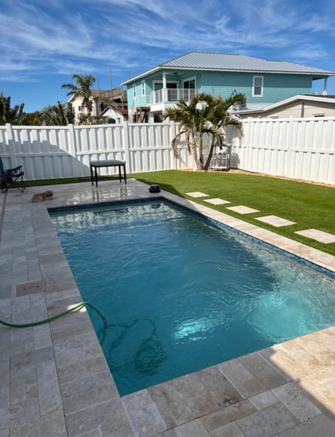 Same poolside backyard after artificial turf installation with a stepping-stone path