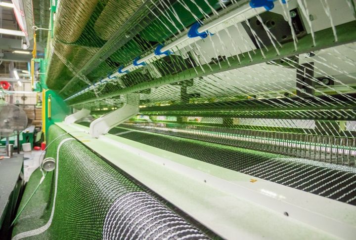 Close-up of yarn threading through the tufting loom