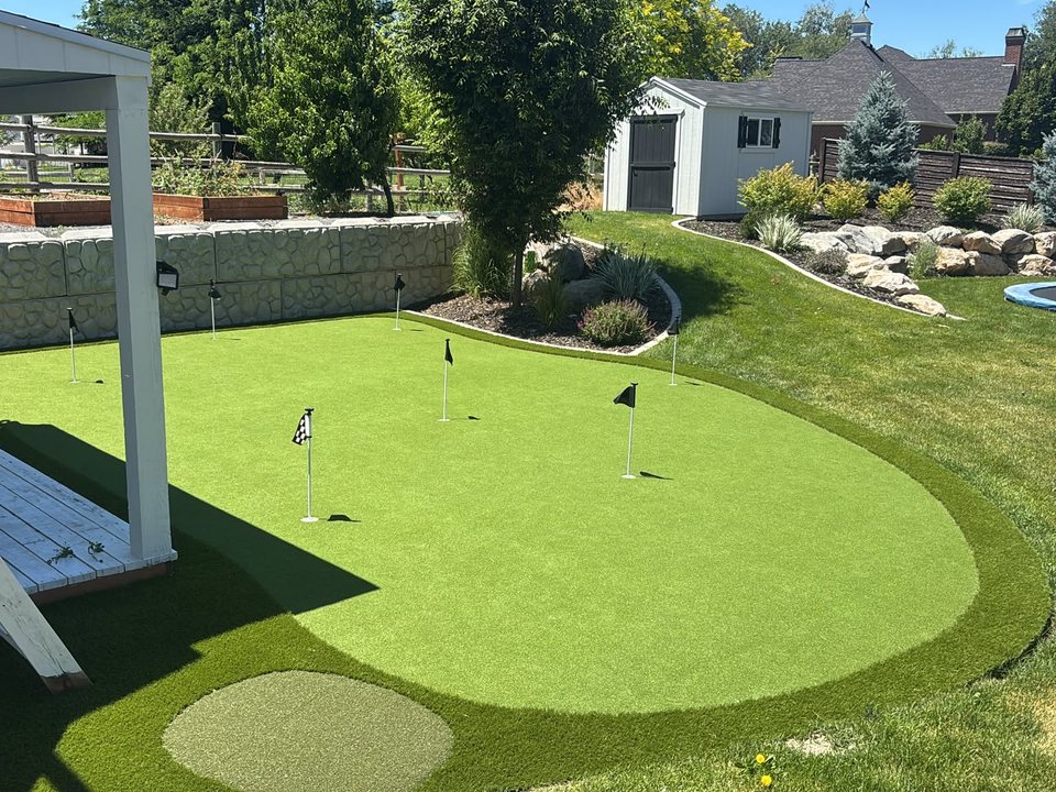 Custom curving backyard putting green with mature landscape planting
